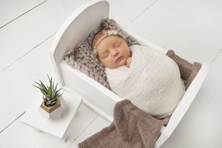 Newborn Baby Girl wrapped in bed with end table